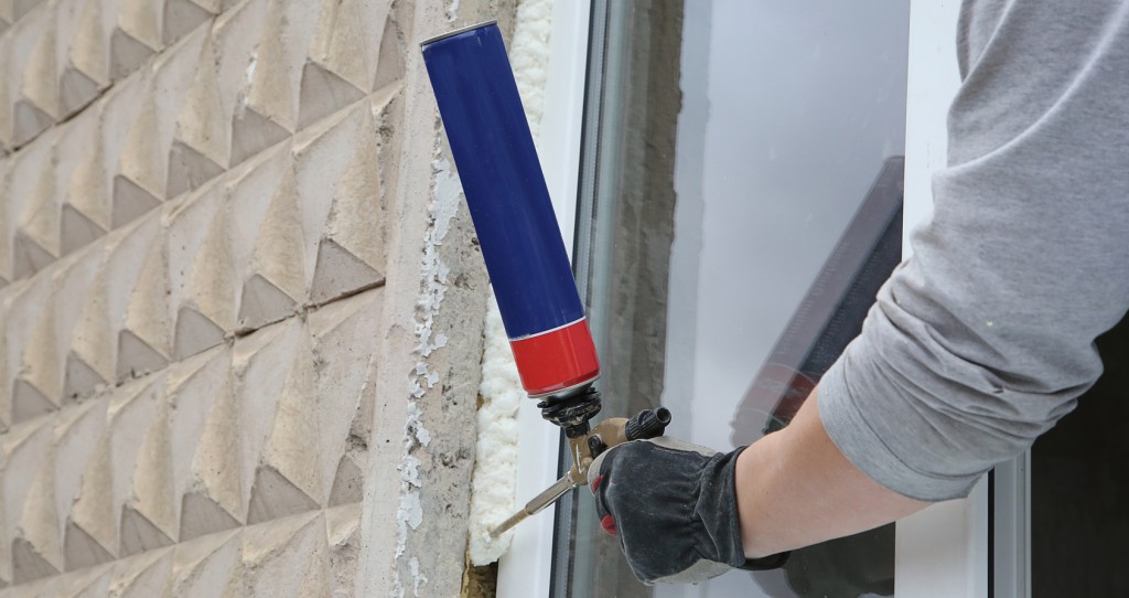 Worker's hand fix a window using polyurethane foam